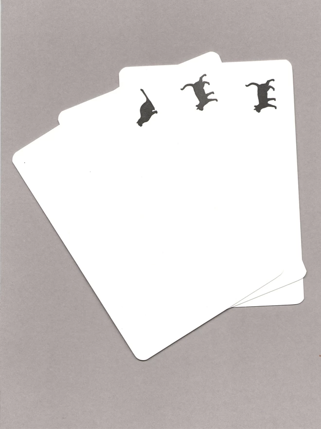 Three notecards with black cats in the bottom corners laid out on a grey background