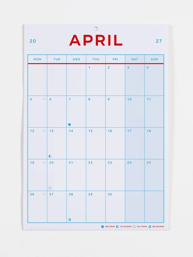 Monthly view calendar in red and blue on white recycled paper, photo shows the month of April