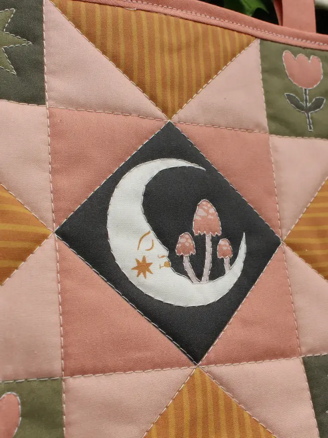 moon folk art quilt hanging. a patchwork hanging quilt with an embroidered moon in the centre.