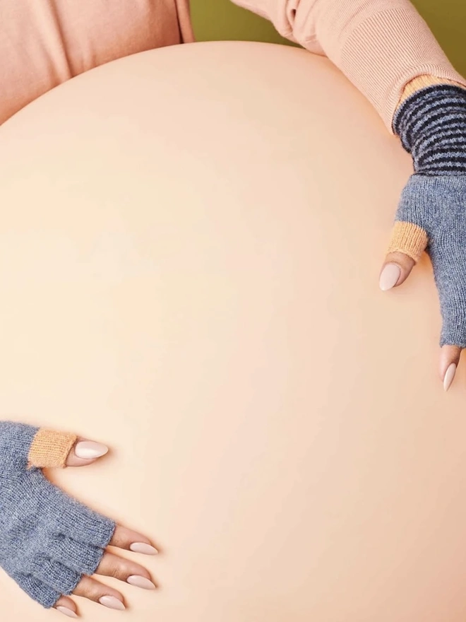 Women's Lambswool Fingerless Gloves, a woman wearing a pair of fingerless gloves holding a balloon. 