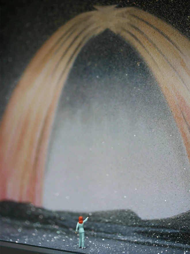 Close up from a miniature scene in an artbox showing a tiny David Bowie looking back at a sparkling cosmic northern lights backdrop.