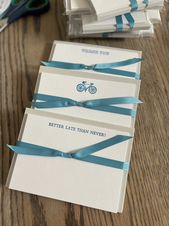 super cool bicycle notecards set. a set of white notecards with blue bicycles illustrated on the top, tied in packs with a blue ribbon. 