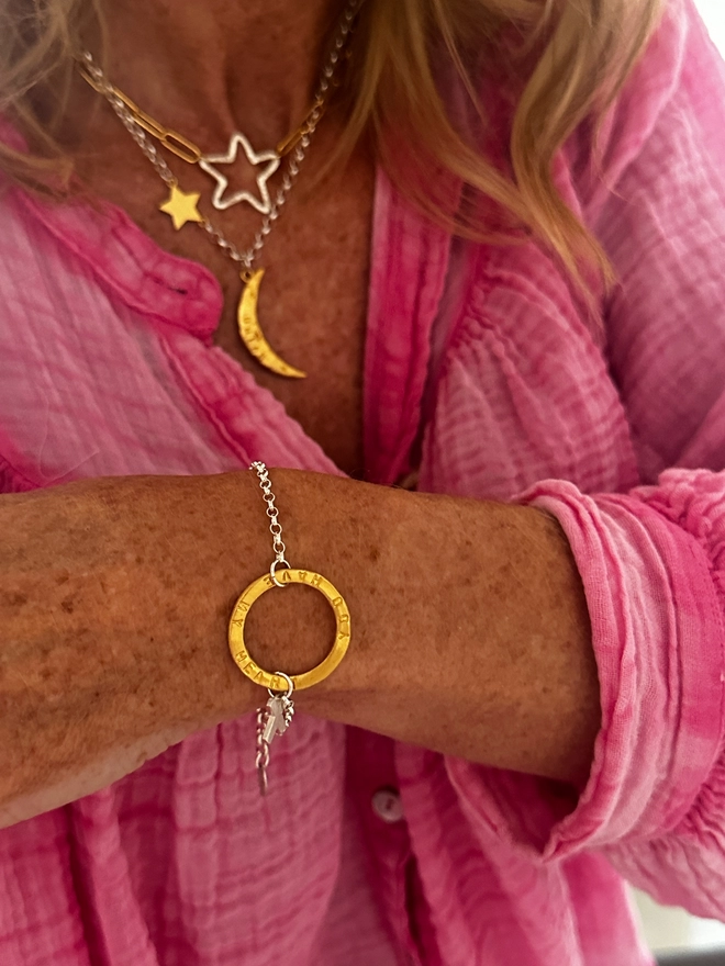 model wears personalised gold halo charm on silver belcher bracelet chain with silver X kiss charm