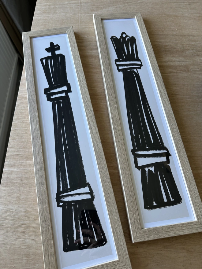 Pair of chess art in wooden frames on a table