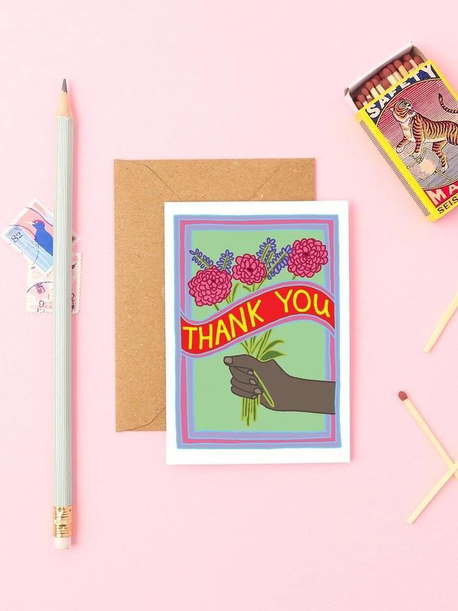 a thank you card with a bunch of flowers. Held by a black hand