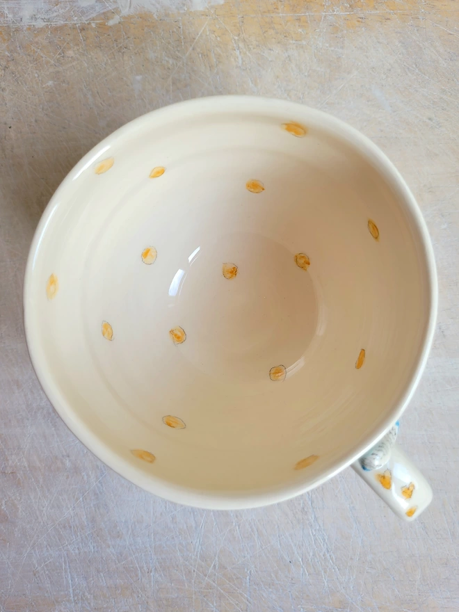 Flatlay of cup with orange hand painted dots and hearts on the handle