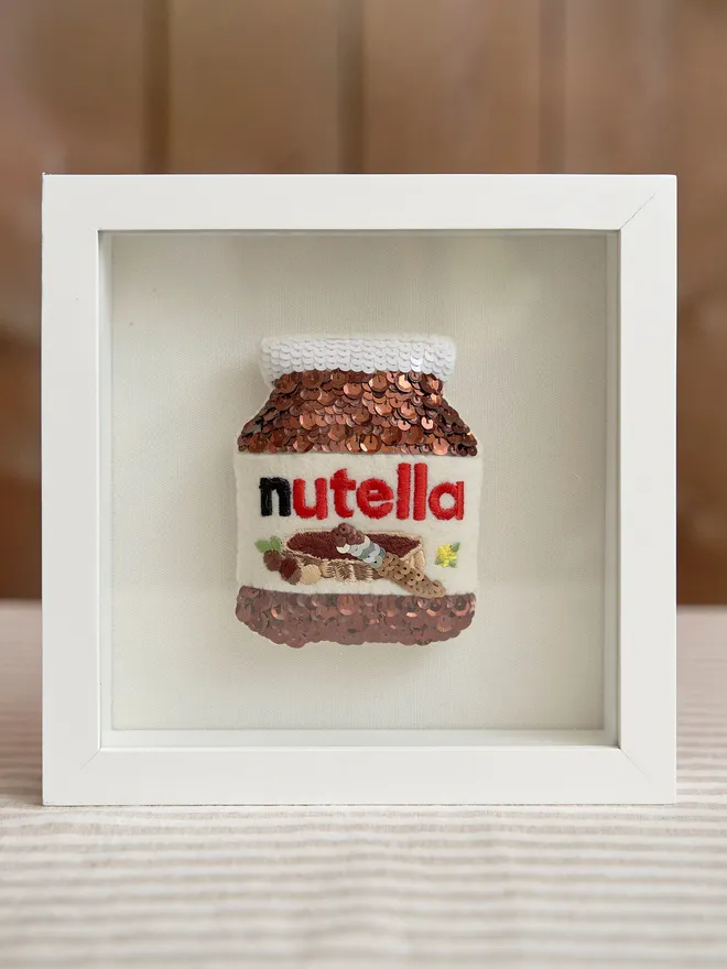 Custom sequin artwork. Nutella jar made from sequins in a white frame. 