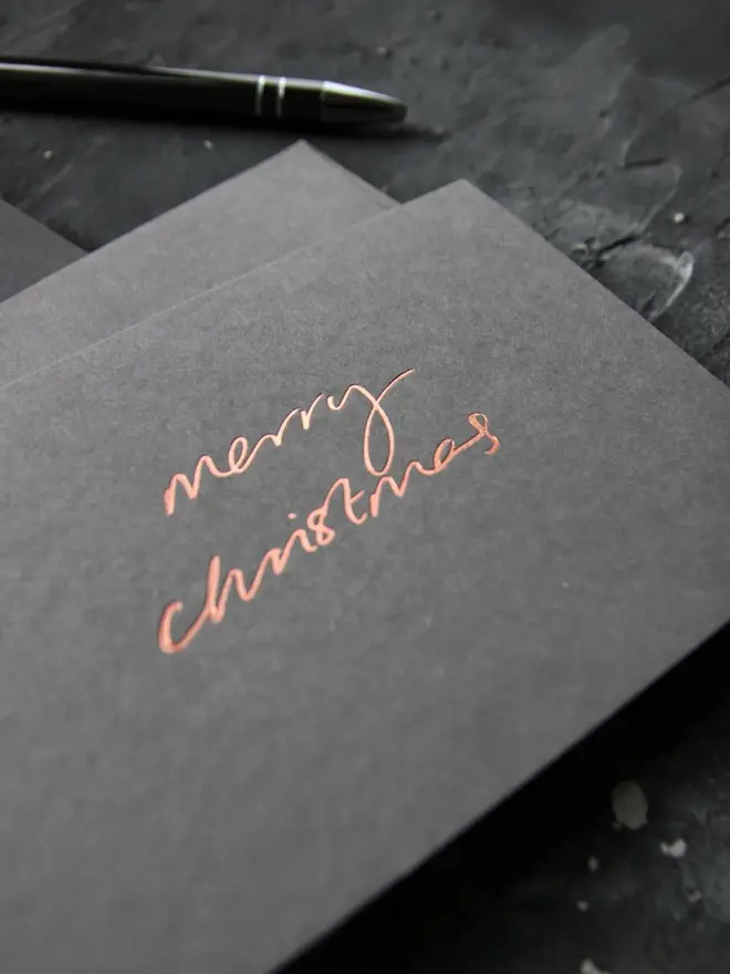 Hand foiled cash card or money wallet in a smoke grey colour in shiny bronze foil text which says ‘merry christmas’.