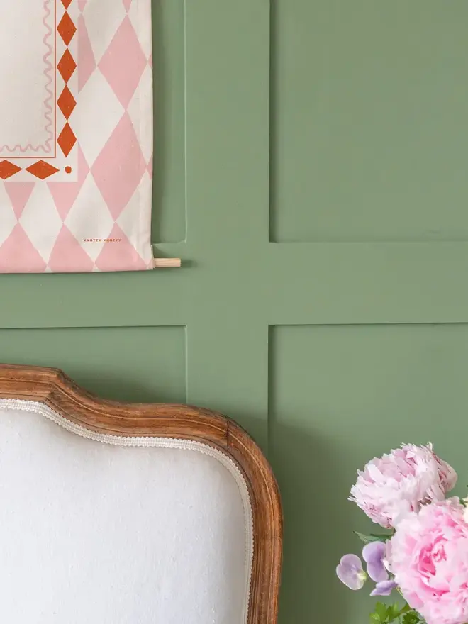 Harlequin Initial Fabric Banner, pink mini and midi next to each other against a green wall. 