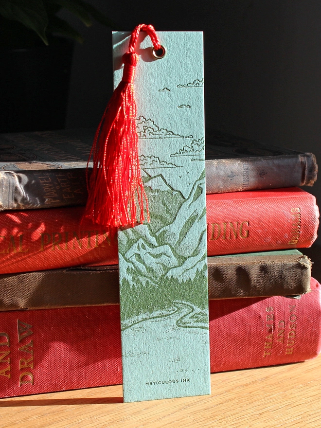 Landscape letterpress bookmark leaning on stack of books