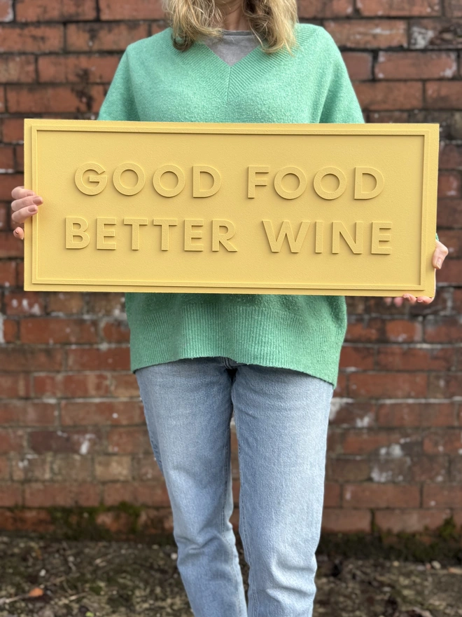 goiod food better wine sign in yellow made by modo against a brick wall
