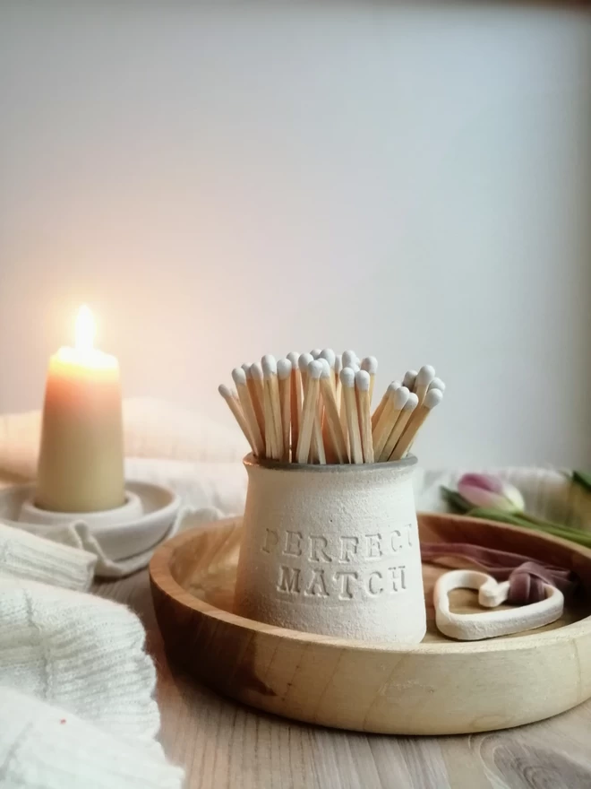 'Perfect Match' match pot sat in a wooden tray with candle in the background, tulip and blanket. White tip matches in the match pot