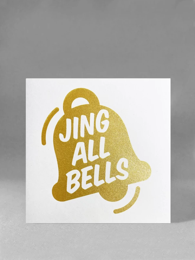  Sparkly gold ink graphic of a bell with the words Jing All Bells within. A square card in a studio set.