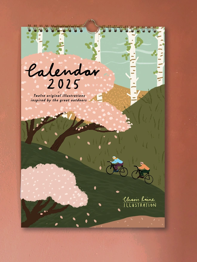 2025 Calendar, filled with 12 original illustrations. Cover shows 2 cyclists on a backdrop of beautiful green hills and cherry blossom trees. A4 size.