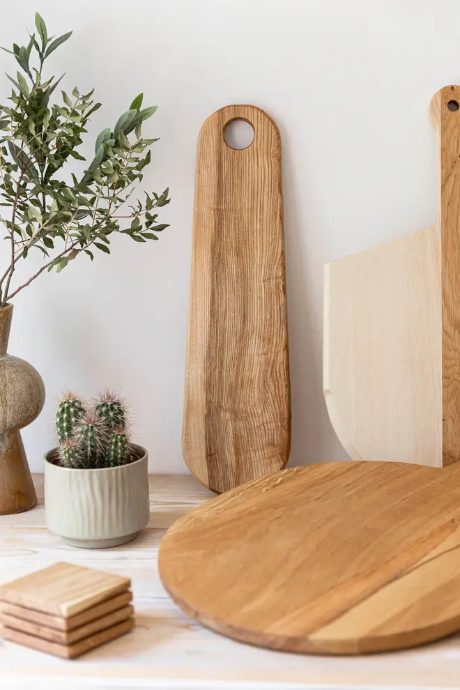 Ash Paddle Serving Board, a wooden serving board sat on a white surface accompanied by other serving boards. 