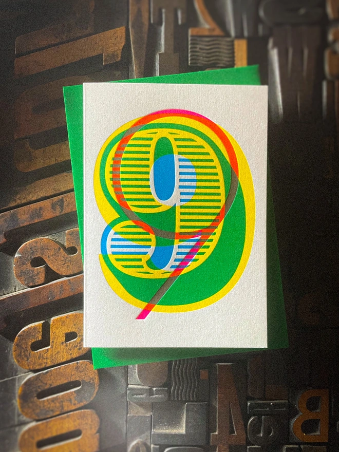Handmade letterpress 9th birthday card featuring bold overlapping numerals printed in vibrant fluorescent cyan, magenta and yellow inks. Each card is individually hand printed using traditional letterpress techniques on luxury paper stock, creating a beautifully tactile finish with a deep impression and rich layered colours inspired by the CMYK printing process. Printed on a traditional letterpress from 1915. A wonderful artisan printed birthday card.