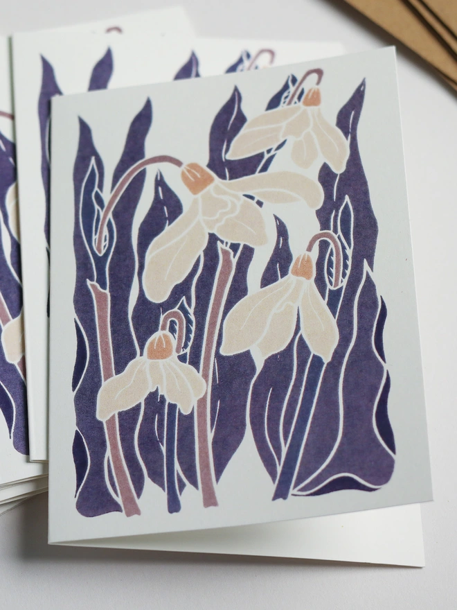 Close-up of Snowdrops in the Night Garden notecard design. Linocut print stationery showing snowdrops in purple and pink colour palette. Bold contemporary colours on A6 recycled cards. Norfolk studio, no AI.