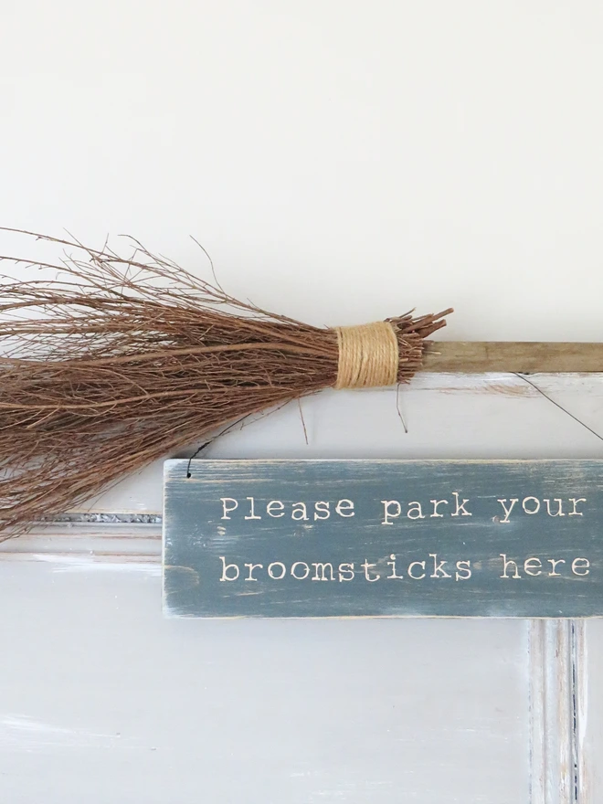 Distressed hand painted wooden sign with broomstick parking message