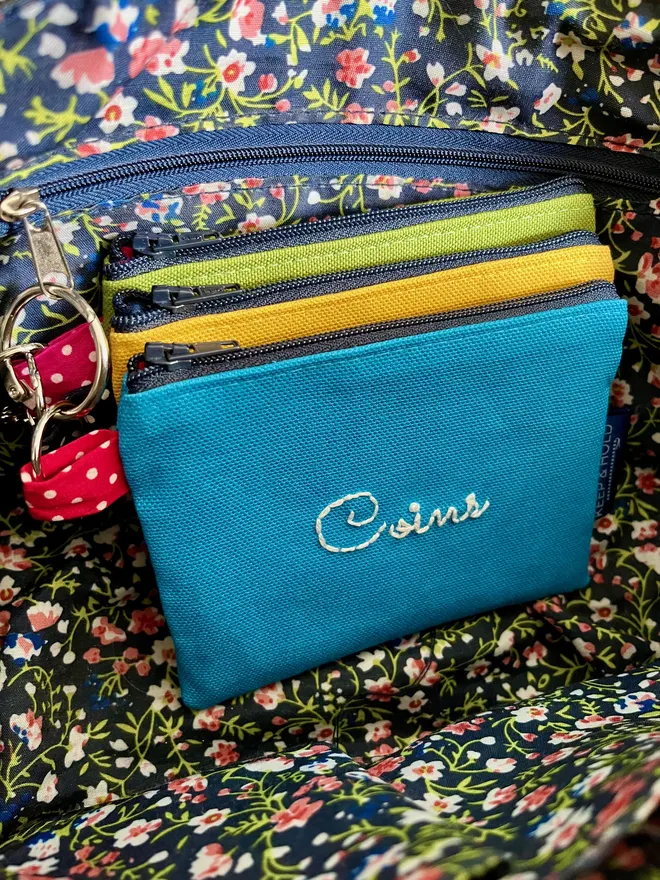 Set of 3 bright coin purses on a keyring, inside a handbag, attached to the zip pull of an inner pocket.