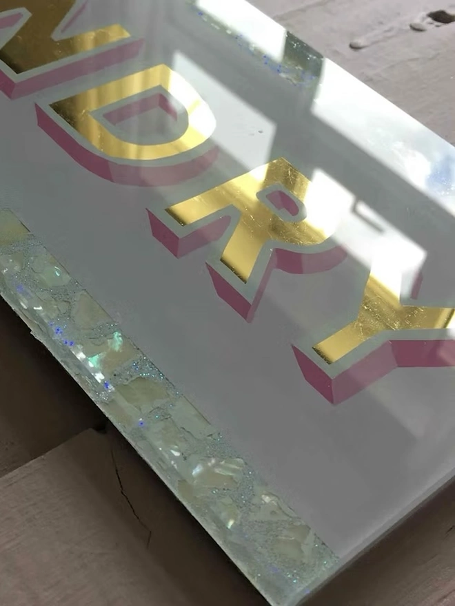 'Laundry' Glass And Gold Leaf Sign, a gold and glass sign sitting on a plain surface. 
