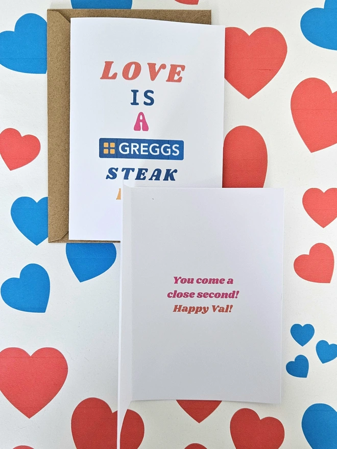 A photograph of the front of a humorous A6 greeting card illustrated using brightly coloured text. The text says love is a Greggs steak bake and inside the card it says you come a close second happy val!