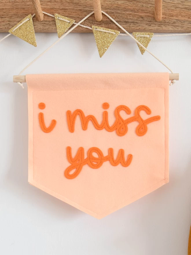 mini felt banner with i miss you written on in orange cursive text.