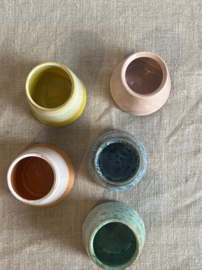 Egg Cup. A bird’s eye view of five egg cups, top to bottom: pink, yellow, blue, orange, green.