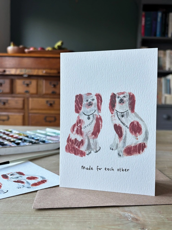 A white greeting card featuring a pair of watercolour painted Staffordshire Pottery Dogs.  The Card reads Made for Each Other  