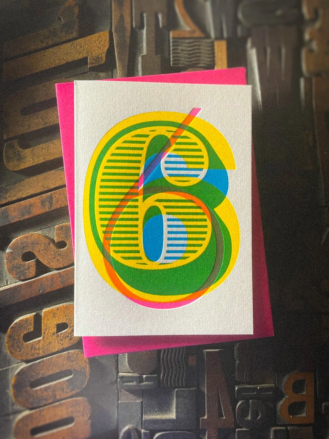 Handmade letterpress 6th birthday card featuring bold overlapping numerals printed in vibrant fluorescent cyan, magenta and yellow inks. Each card is individually hand printed using traditional letterpress techniques on luxury paper stock, creating a beautifully tactile finish with a deep impression and rich layered colours inspired by the CMYK printing process. Printed on a traditional letterpress from 1915.