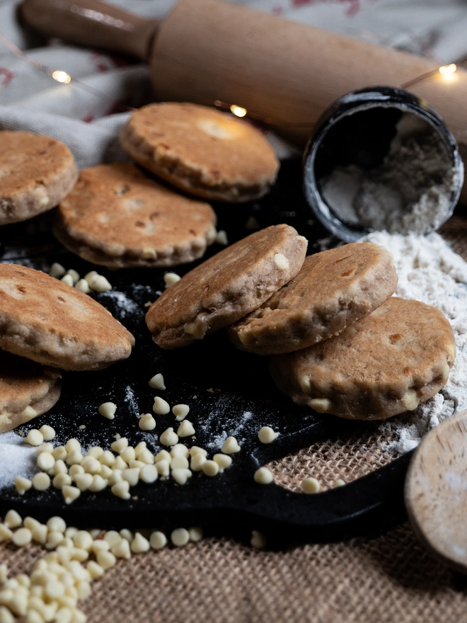 White Chocolate Chip Welsh Cakes on a griddle with loose messy ingredients