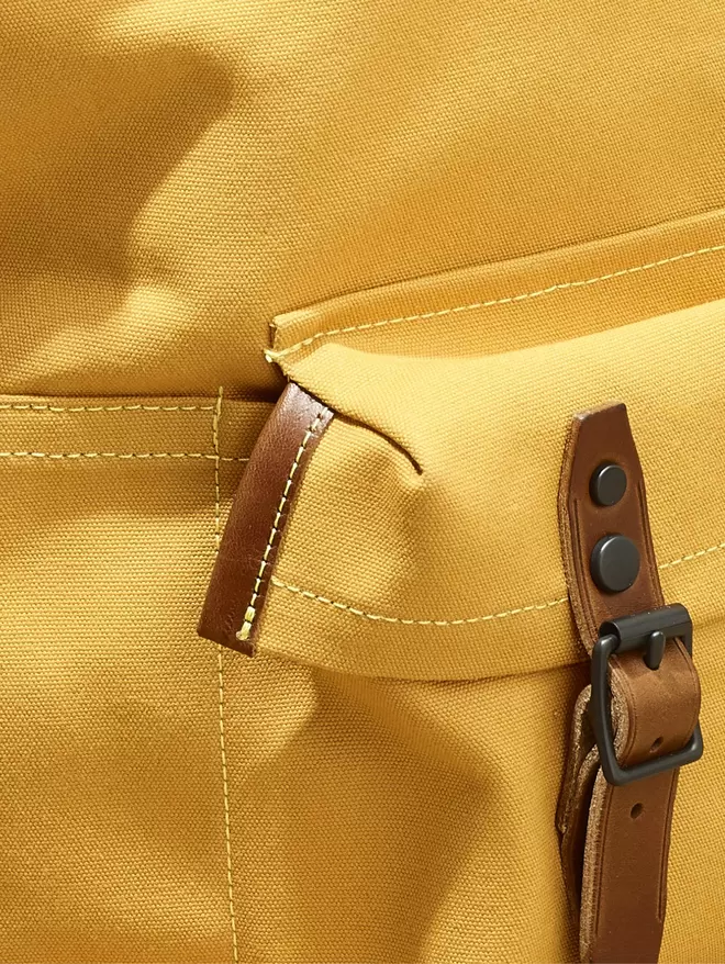 Close up of the pocket on of the yellow Shortwood back pack with brown leather trim and black hardware.