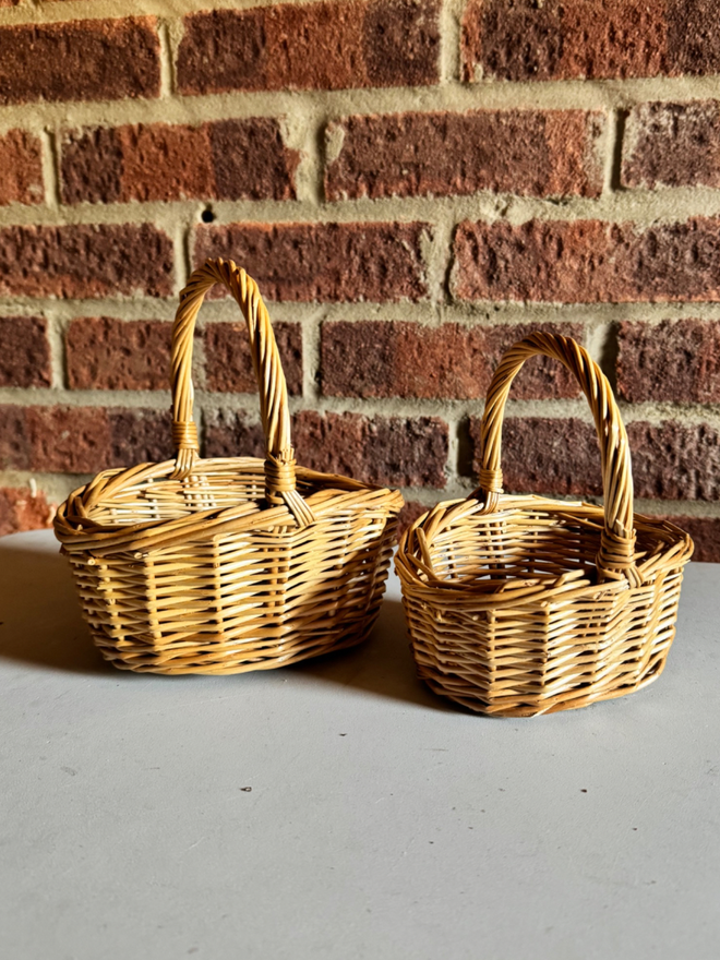 Set of 2 wicker baskets displayed in front of brick wall