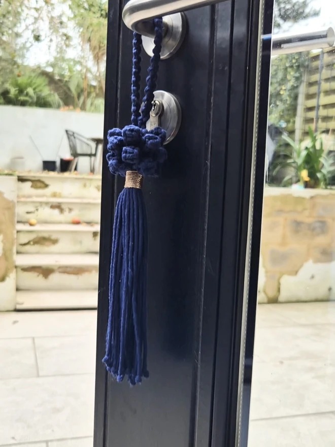 Handmade hanging door tassel in navy, and natural, featuring decorative knots with a tasseled end. Its rich in texture and charm, offering a sophisticated and elegant accent to any space.