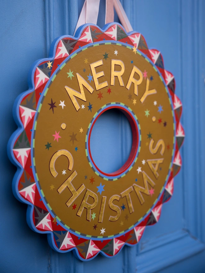 Multicoloured Hand painted Christmas Wreath with gold leaf lettering on a blue front door