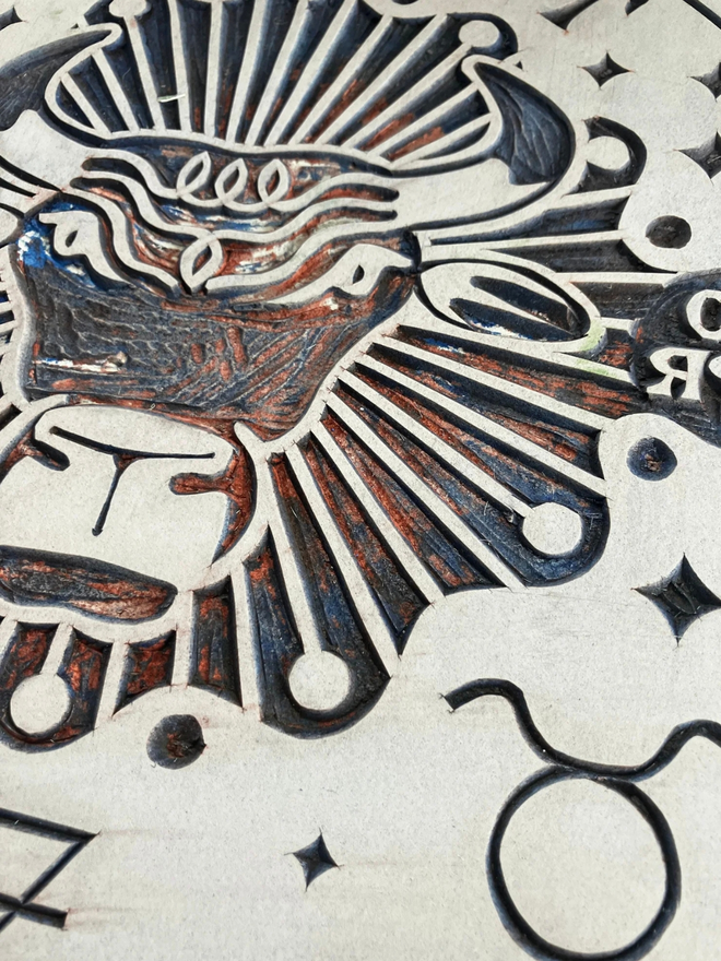 taurus zodiac linocut. a bull and zodiac symbols linocut and printed on a blue background.