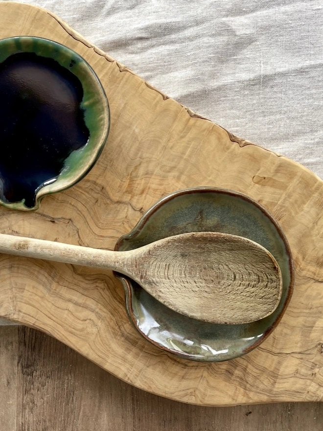 A green and birch Ceramic Spoon Rest on a table with a linen tablecloth and a wooden spoon
