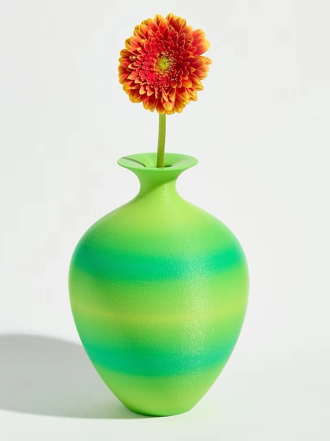3d printed vase in green stripes with bright pink flower