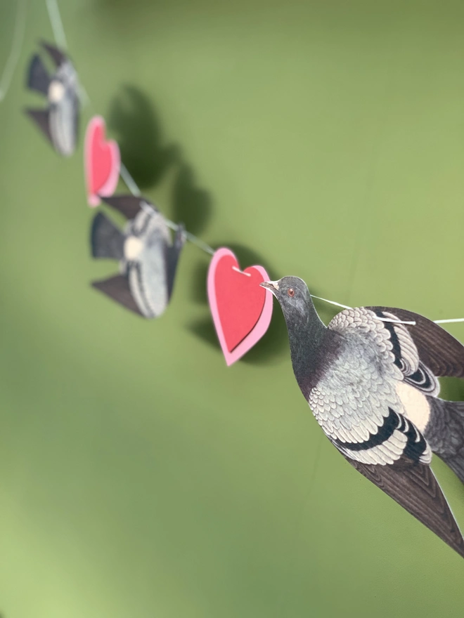 a string of bunting with pigeons and red and pink hearts