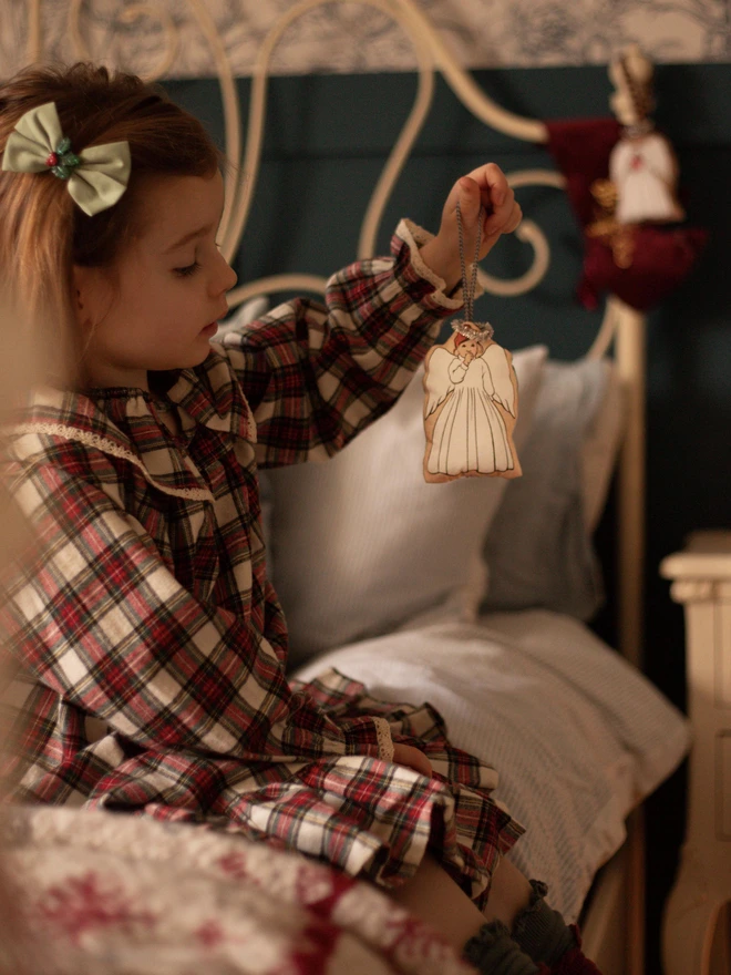 a little girl holding a little angel Christmas tree decoration