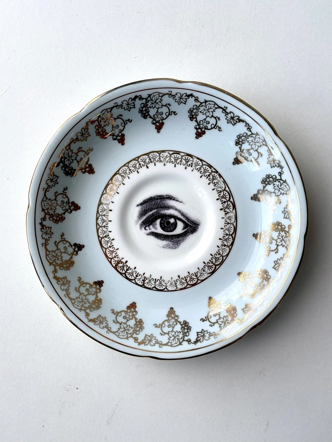 vintage plate with ornate border has a black and white image of a victorian eye in the centre