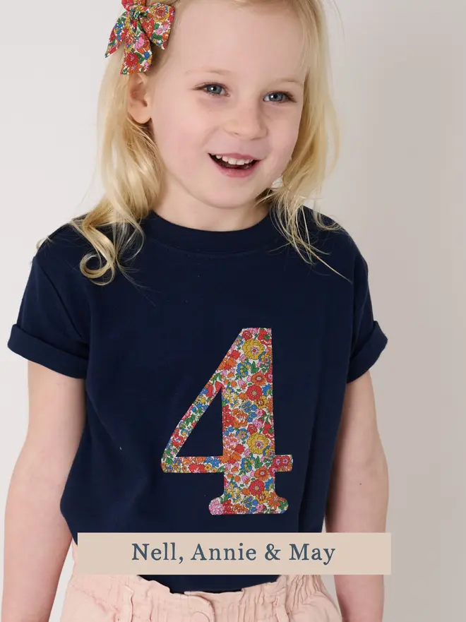 A birthday girl wearing a navy birthday t-shirt with a number 4 cut from liberty floral print on the front