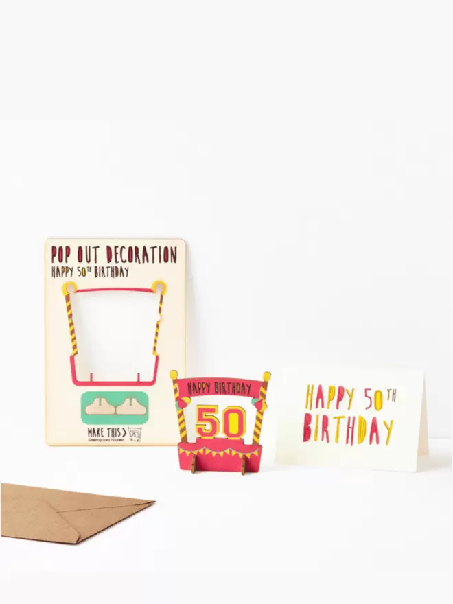 Fiftieth birthday decoration and fiftieth birthday card and brown kraft envelope on a white background