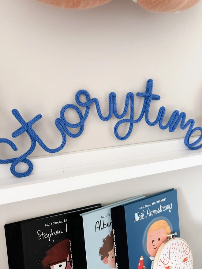 Knitted storytime kids reading area decor or book nook sign on a shelf with some childrens books on display