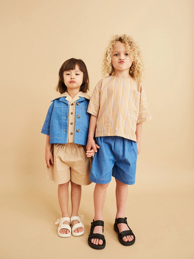 cool kids in summer children's clothes wearing denim and beige oversized tops and stylish shorts made by cool uk kids brand studio koter started by former cos duo