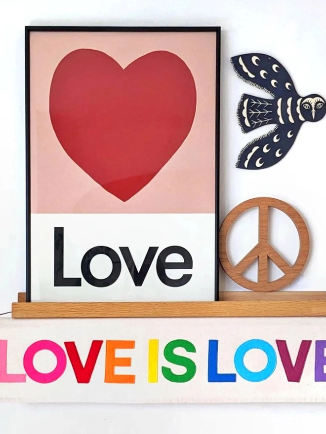 framed illustrated love heart wall print with the word Love at the bottom propped on a shelf 