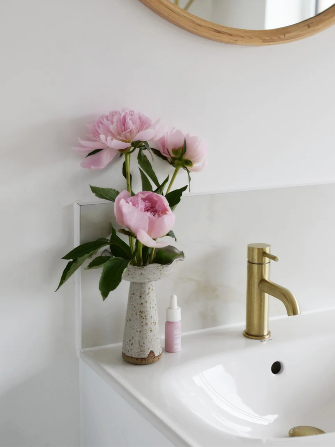 Wavy pedestal vase. A stoneware hand thrown pedestal vase on a bathroom sink