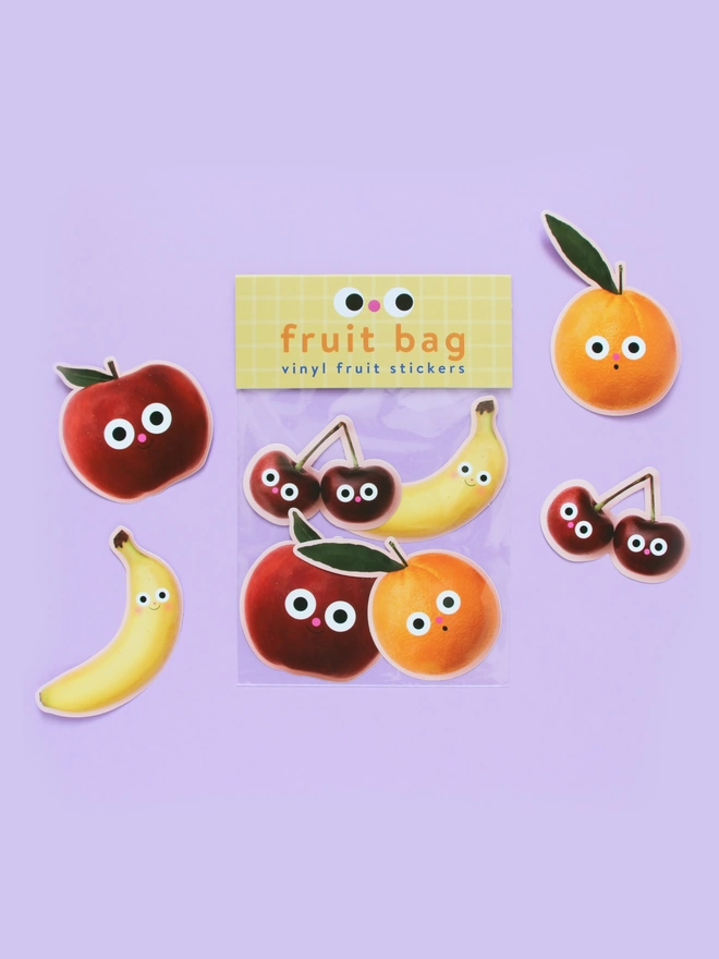 A Fruit bag of vinyl stickers. Each pack Includes a Banana, Red apple, Orange & a pair of cherries