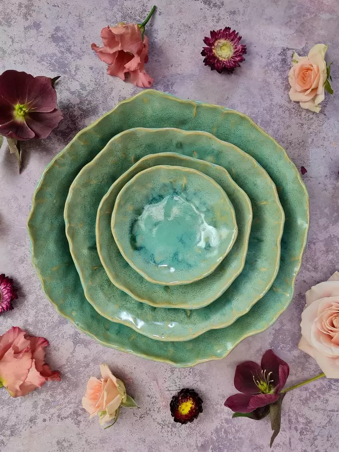 Tableware, serveware, Nesting set of four handcrafted ceramic bowls in an Aqua glaze with turquoise and greens, breakfast bowl, serving bowl, gift, potter, tableware, dinnerware, photographed on a pink background with flowers.