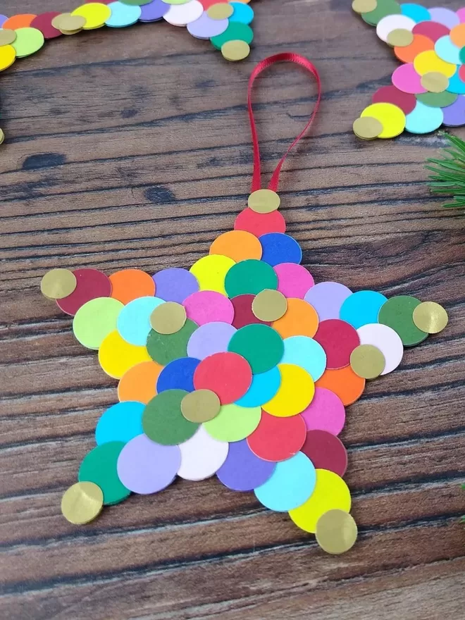 Closeup of small Rainbow Star Christmas Ornament. Solid star shape covered in multicoloured circles.