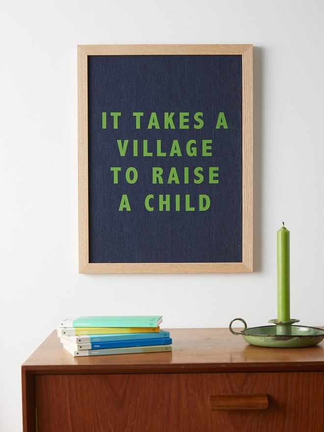 It takes a village to raise a child navy linen picture with green writing 